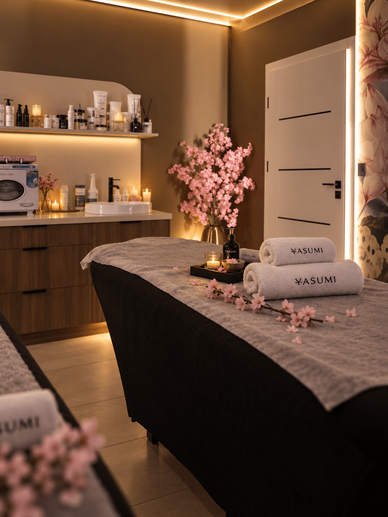 Gabinet SPA YASUMI z łóżkiem zabiegowym, ręcznikami YASUMI, kwiatami i kosmetykami